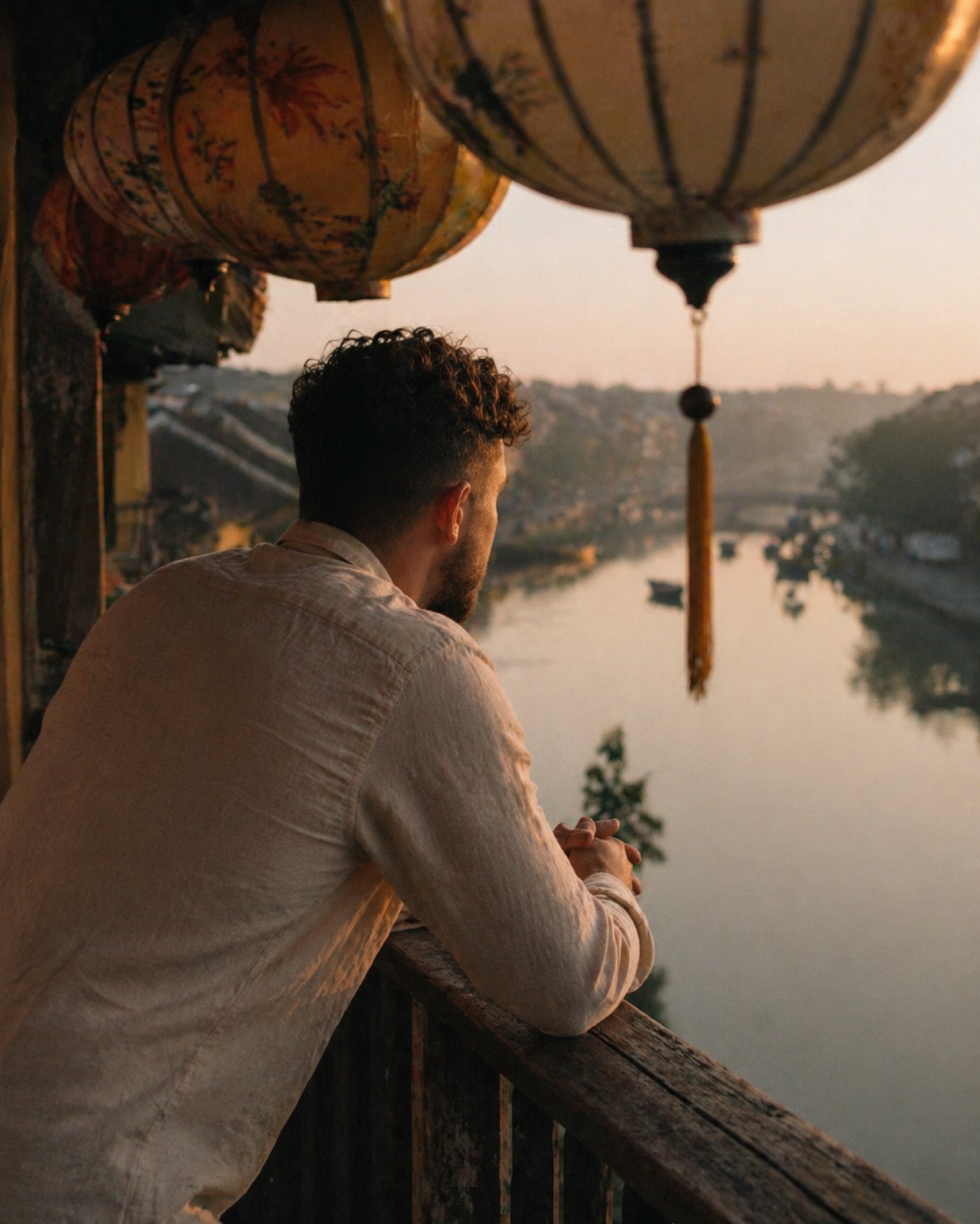 Daniël looking out over a river at sunset, lanterns above, Hoi An, Vietnam