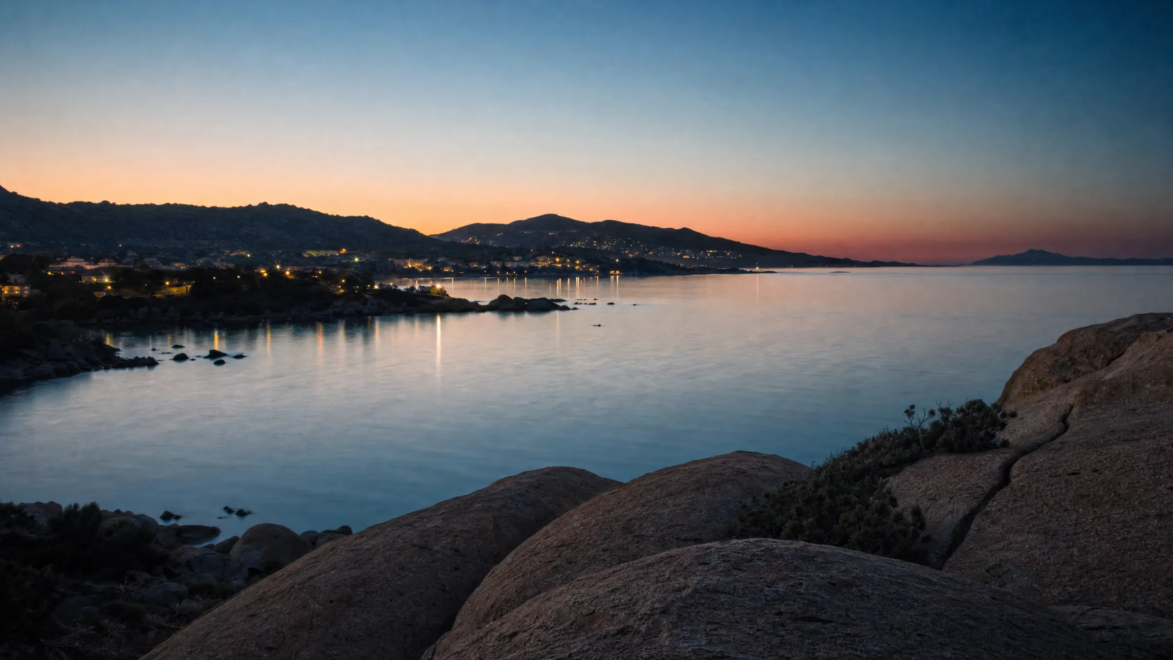 A quiet bay at blue hour with the lights of a small town along the shore