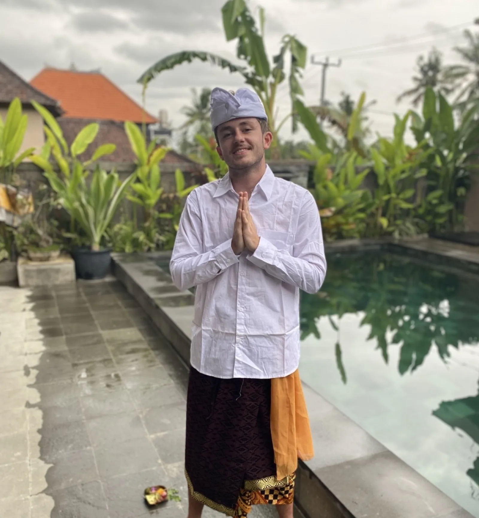 Daniel in Balinese dress beside a pool
